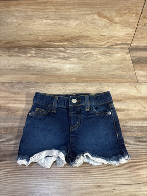 Front view of Cat and Jack toddler denim shorts showcasing eyelet lace trim and frayed hem on a light wood floor