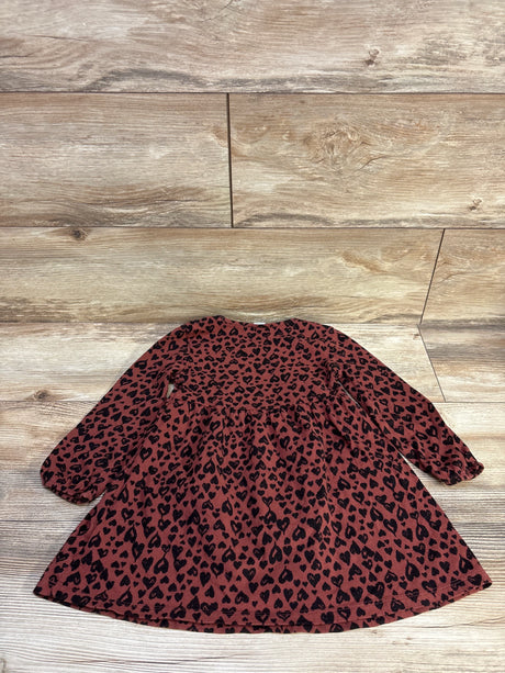 Flat lay of Old Navy brown long-sleeve toddler dress showcasing gathered waist and elastic cuffs with black heart-print on light wood floor