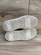Closeup of kids sneaker soles with chevron tread on wood floor