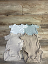 Flat lay of H&M organic 4-pack kimono bodysuits showcasing short sleeves, envelope necks, and snap crotches with wood floor background