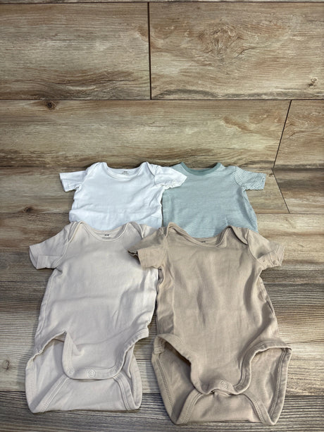Flat lay of H&M organic 4-pack kimono bodysuits showcasing short sleeves, envelope necks, and snap crotches with wood floor background