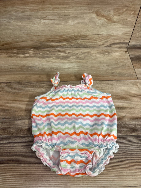 Top view of Old Navy bubble romper in white with wavy rainbow stripes, tie shoulder straps and snap crotch on wood background