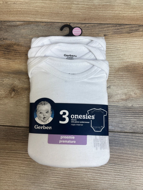 Front view of three white Gerber preemie bodysuits in packaging on a wood surface
