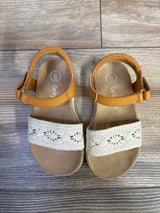 Top view of toddler Cat & Jack sandals showing white crochet toe straps and tan ankle strap on wood floor