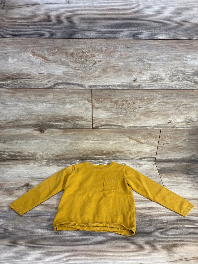 Front flat lay of H&M fine-knit yellow toddler sweater showcasing small chest patch pocket and crew neck on wood-plank background