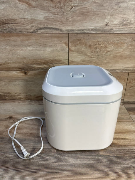 White electric wipe warmer with power cord on wood background, baby gear essential
