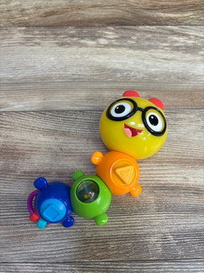 Top view of Baby Einstein Twist-a-Pal Cal showing yellow head with glasses and colorful linked segments with rattle on wood