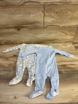 Top-down view of two newborn light blue footed sleepers showcasing one polar bear print and one solid design with wooden floor background