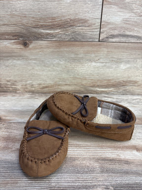 Brown suede moccasin slippers with plaid lining and decorative bow on wooden floor