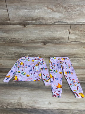 Flat lay of purple toddler unicorn pajama set showing long-sleeve top and cuffed pants with all-over unicorn print on wood floor