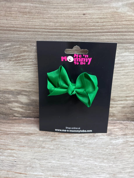 A solid green grosgrain hair bow attached to a Me n Mommy To Be display card.