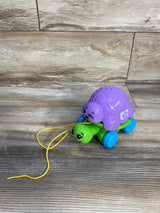Angled view of LeapFrog Nest & Count Turtle Tower with purple shell, green base, blue wheels and yellow pull string