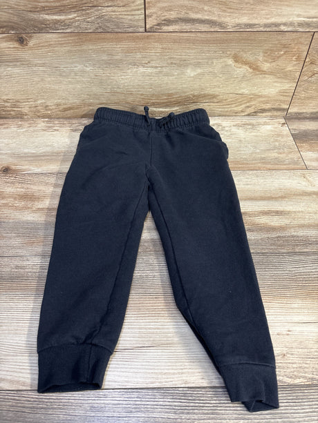 Flat lay of toddler black Carter’s drawstring joggers size 5T showing elastic waistband with drawstring and ribbed ankle cuffs on light wood background