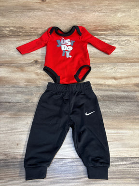 Red Nike baby onesie with 'Just Do It' graphic paired with black jogger pants, ideal for infant sporty outfits.