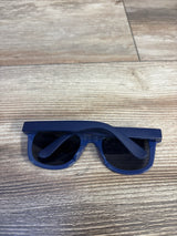 Top view of Just One You kids sunglasses in blue showing folded temples and dark lenses on a light wood surface