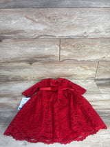 Flat lay of girls red glitter lace party dress showcasing long sleeves, bow at waist, and scalloped hem on light wood floor