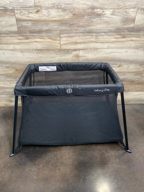 Front view of NEW Dream On Me Travel Light Playard in black showcasing mesh sides and padded rim on concrete floor