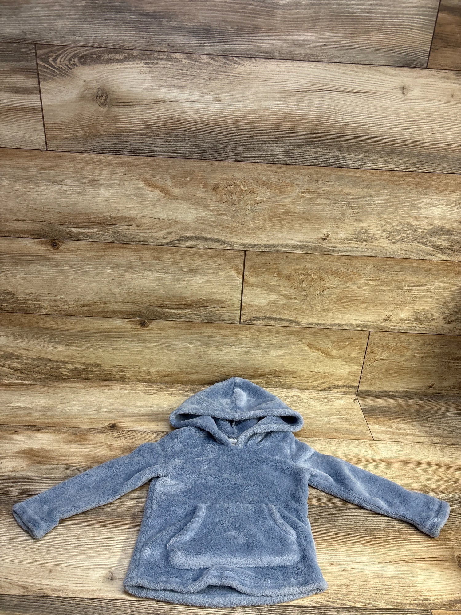 Front view of Carter’s blue plush hooded pullover sweatshirt in size 3T with long sleeves and kangaroo pocket on wood floor
