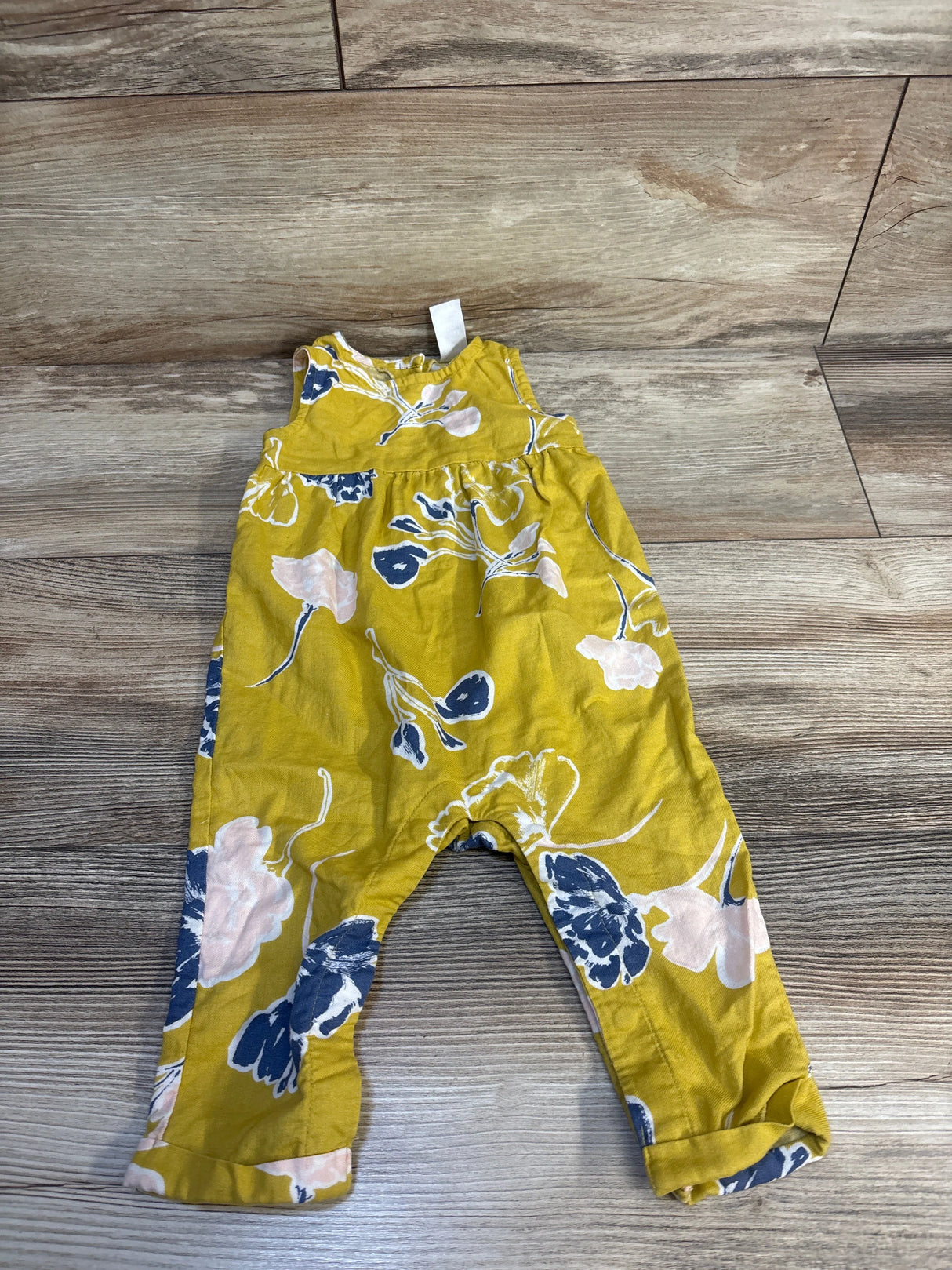 Yellow floral baby romper with blue and pink flowers on wooden floor