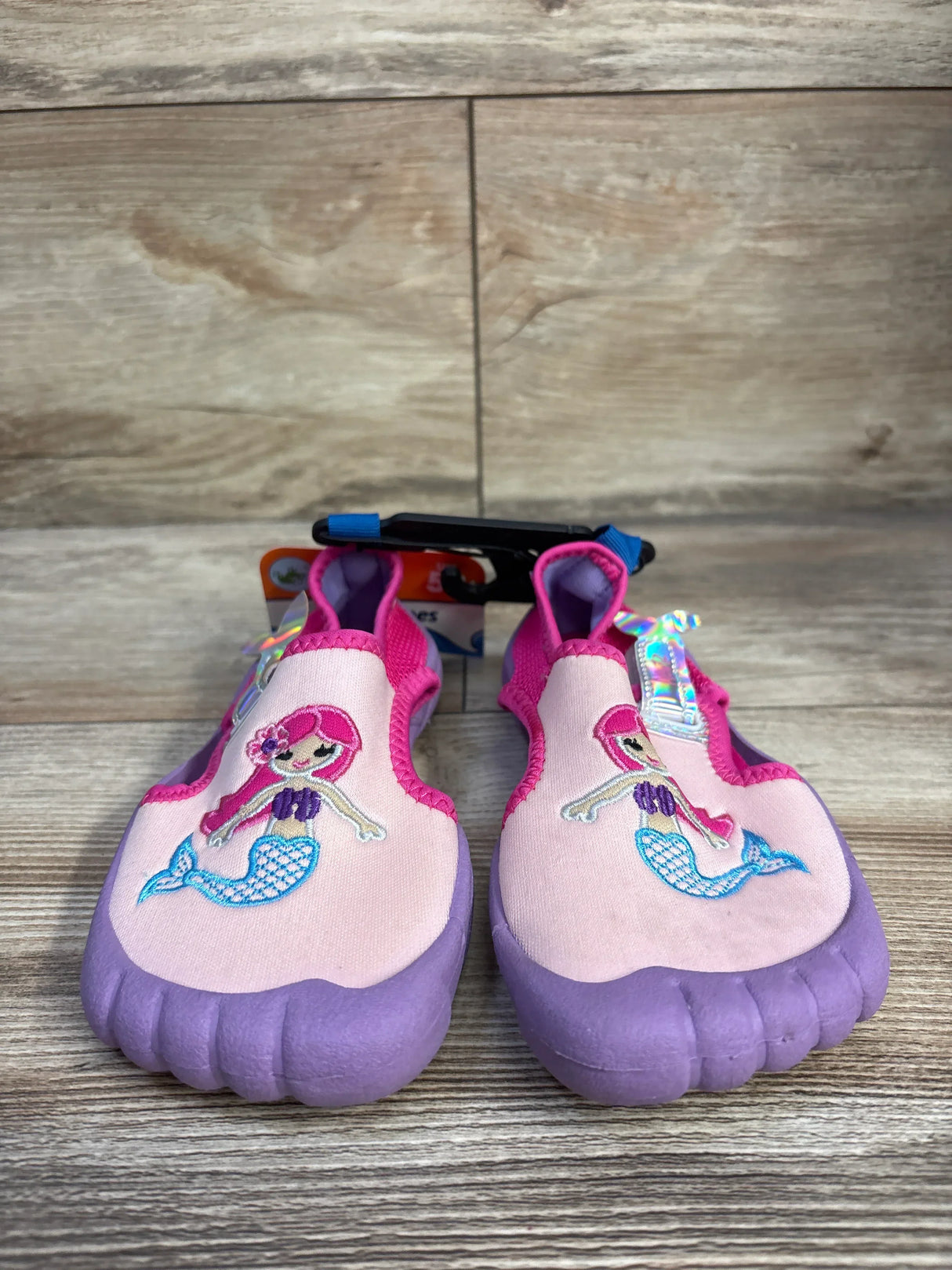Front view of Newtz toddler mermaid water shoes with embroidered mermaid, purple soles, slip-on style on wood background
