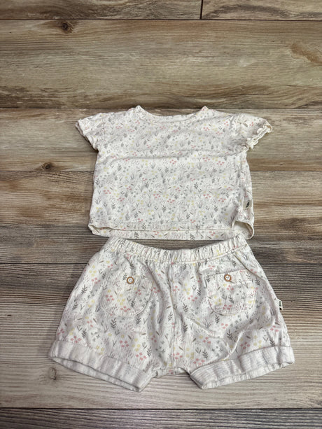 Top-down view of ivory Easy Peasy shirt and shorts set showcasing floral print, pockets, and elastic waist on wood