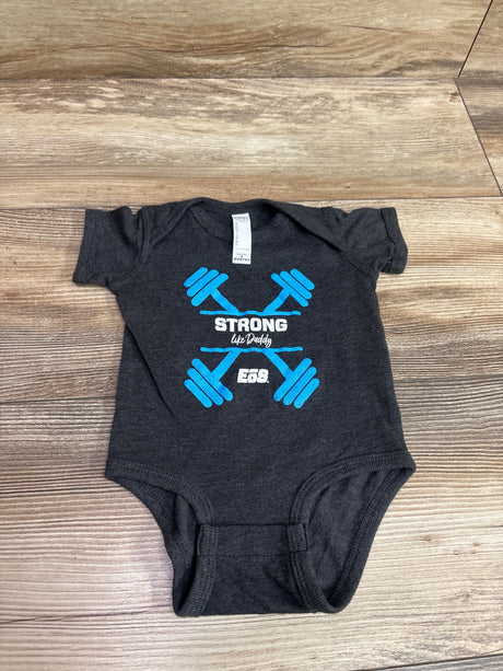 Front view of Grey Rabbit Skins EOS bodysuit showcasing blue dumbbells and Strong like Daddy graphic on a wood floor