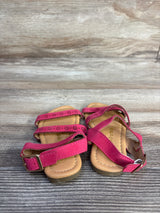 Top view of Ositos pink slingback sandals showing three perforated straps and an adjustable buckle on wood background