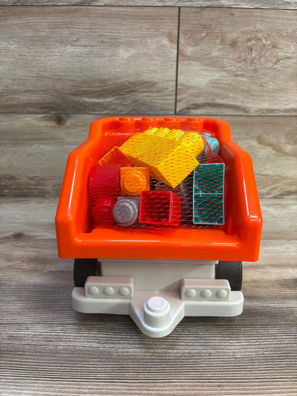 Rear view of Battat dump truck with orange bed and 17-piece colorful building blocks in a net bag