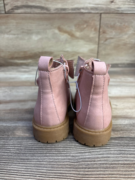 Rear view of pink toddler ankle boots showing back zipper, pull tab, bow detail and tan lug sole on wood floor background