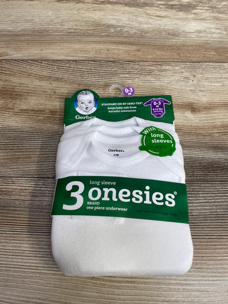 Pack of three white Gerber long sleeve baby onesies for 0-3 months on wood background