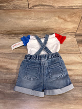 Flat lay of Cat & Jack denim suspender shorts set showing crossed suspenders, elastic waist and rolled cuffs on wood floor