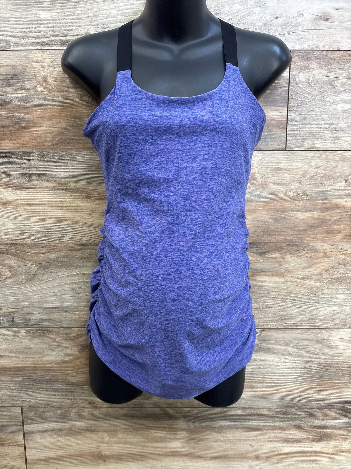 Front view of purple spacedye maternity cami with black shoulder straps and gathered side ruching on mannequin against wood plank background