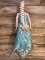 Rear view of 32-inch Jakks Elsa doll showing long braided blonde hair and turquoise snowflake dress on wood background