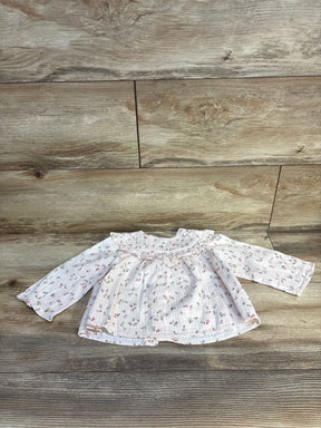 Floral baby blouse with ruffled collar on wooden floor