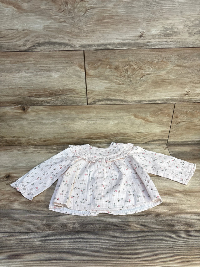 Floral baby blouse with ruffled collar on wooden floor
