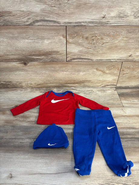 Red long sleeve baby shirt, blue pants, and blue hat set with white logo on wood floor