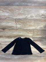 Flat lay of Children's Place black long-sleeve toddler shirt, size 2T, new with tags on wood background