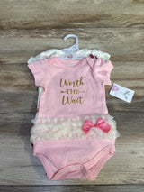 Flat lay of a 3-pack of baby bodysuits showing a pink bodysuit reading Worth the Wait with tulle ruffle and pink bow on wood background