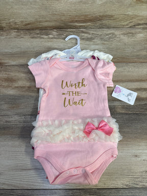 Flat lay of a 3-pack of baby bodysuits showing a pink bodysuit reading Worth the Wait with tulle ruffle and pink bow on wood background