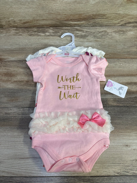 Flat lay of a 3-pack of baby bodysuits showing a pink bodysuit reading Worth the Wait with tulle ruffle and pink bow on wood background
