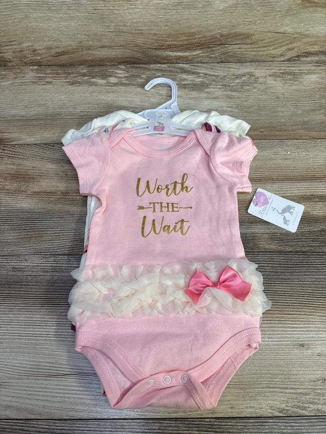 Flat lay of a 3-pack of baby bodysuits showing a pink bodysuit reading Worth the Wait with tulle ruffle and pink bow on wood background