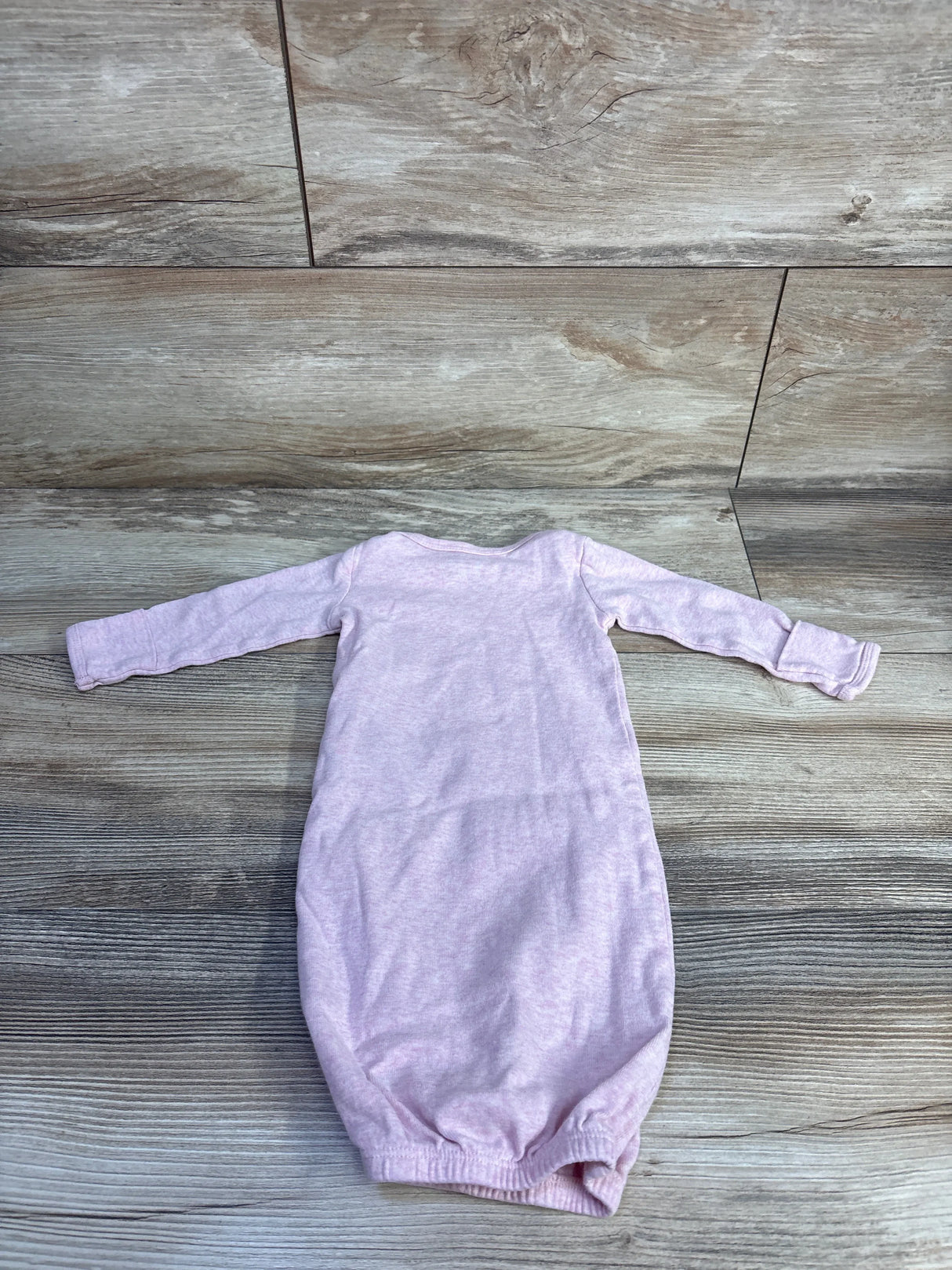 Flat lay of Simple Joys Bunny newborn pink sleep gown showing long sleeves and gathered elastic hem on wood floor background
