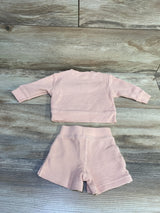 Flat lay of Carter's x Hilary Duff newborn pink thermal two-piece set showing waffle knit texture on a wood floor background