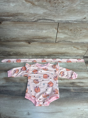 Pink baby onesie with ruffles and pumpkin and flower pattern on wooden floor, plus matching headband