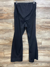 Front view of black maternity flared yoga pants showcasing high rise belly panel and flared legs with wood background