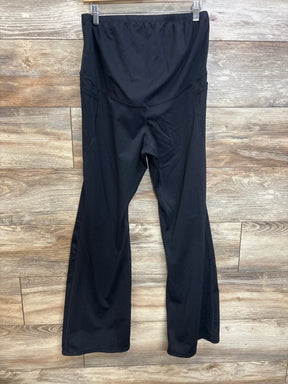 Front view of black maternity flared yoga pants showcasing high rise belly panel and flared legs with wood background