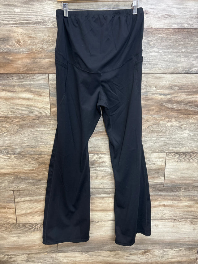 Front view of black maternity flared yoga pants showcasing high rise belly panel and flared legs with wood background