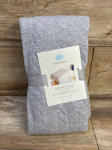 Front view of Cloud Island grey quilted changing pad cover folded, showing diagonal stitching and label on wood background