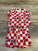 Top-down view of red-and-white checkered baby shirt and shorts with blue stars, wooden buttons and elastic waistband on wood background