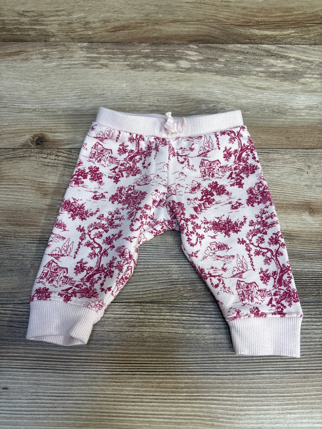 Pink baby pants with maroon countryside print on wood surface
